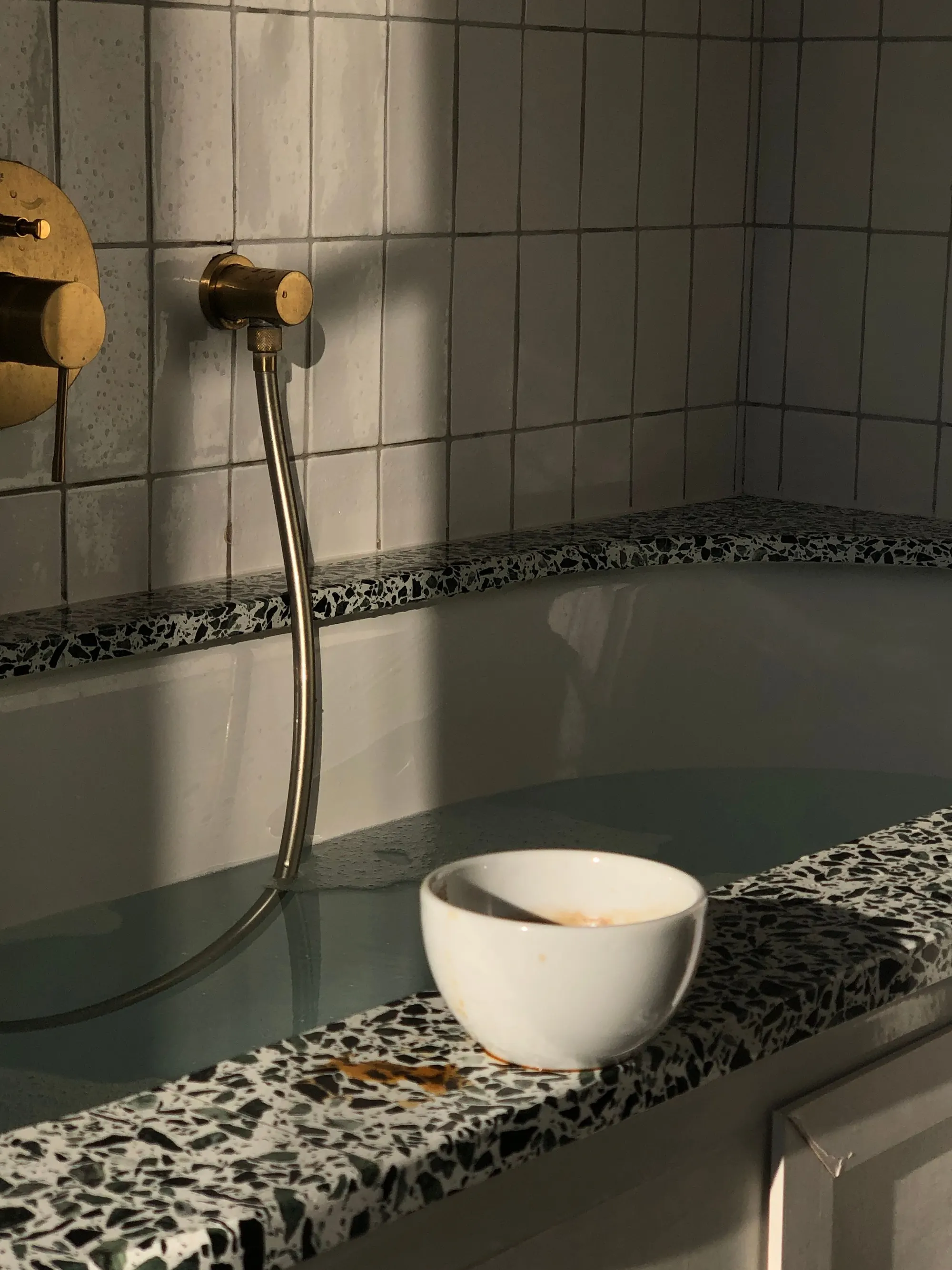 Terrazzo-tiled bath with brass tapware